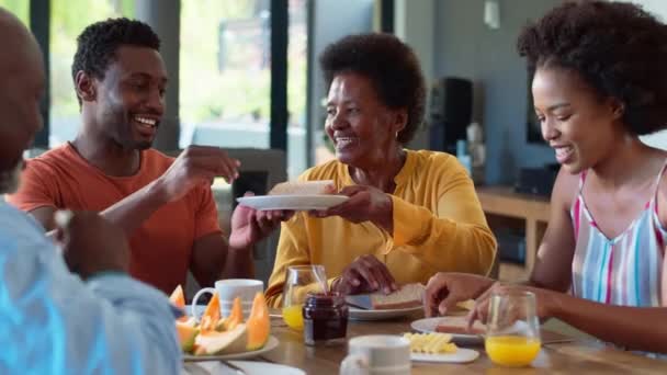 家庭でテーブルの周りに一緒に朝食を食べるシニアの両親や大人の子供と朝食を持っている家族 スローモーションで撮影 — ストック動画