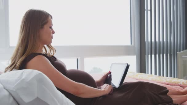 Pregnant Woman Lying Bed Home Watching Film Digital Tablet Whilst Stock Video