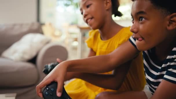 哥哥和姐姐坐在家里沙发上 手里拿着控制器 一起玩电子游戏 动作缓慢 — 图库视频影像