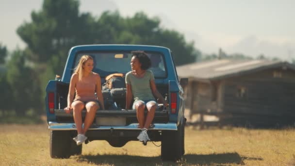 友人としてピックアップトラックに乗って2人の女性が田舎を通り抜けるロードトリップを楽しむ スローモーションで撮影 — ストック動画