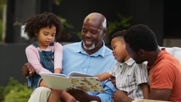 Multi Generational Family Sitting Garden Home Having Fun Reading Book — Stock Video
