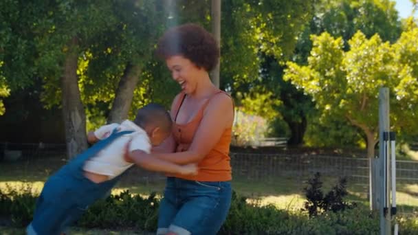 夏の庭で若い息子と遊ぶ母は彼を回転させました スローモーションで撮影 — ストック動画
