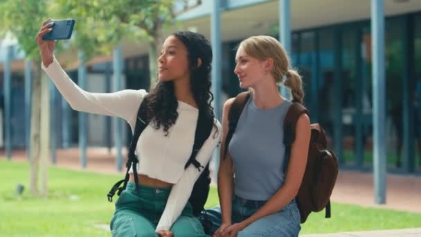 Két Középiskolás Lány Kint Falon Szelfiznek Mobiljukon Lassított Felvételen Forgatják — Stock videók