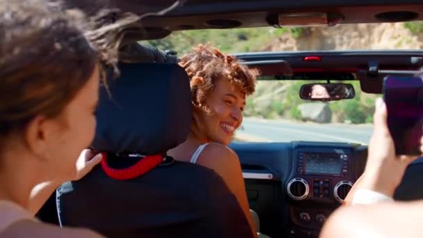 オープントップカーの女性の友人のグループ 田舎を介して道路旅行で笑う スローモーションで撮影 — ストック動画
