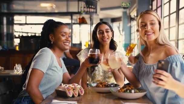 レストランで会う多文化の女性の友人のグループは 食べ物が到着し チアをするように携帯電話でセルフィーをポーズします スローモーションで撮影 — ストック動画