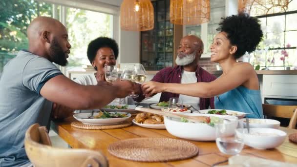 家庭でテーブルの周りに座っているシニアの両親と大人の子供を持つ家族は 食事をする前にワインでチアをすることを祝います ゆっくり動きで撮影 — ストック動画
