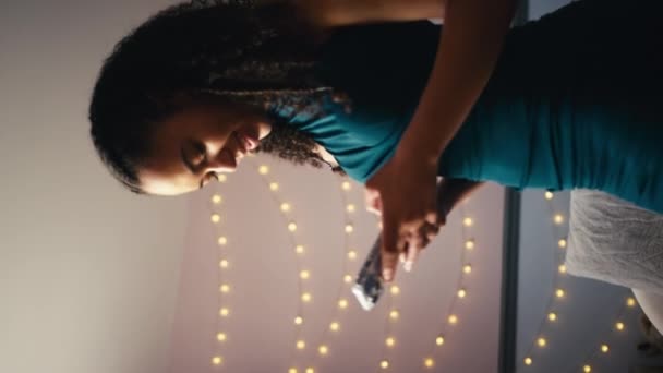 ベッドルームの自宅の10代の少女の垂直ビデオは ミラーでメイクアップし 携帯電話を使用してプロムや夜の準備をする スローモーションで撮影 — ストック動画