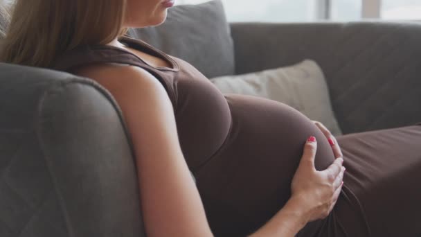 Gravid Kvinne Som Slapper Sofaen Hjemme Berører Magen Føler Babyen – stockvideo