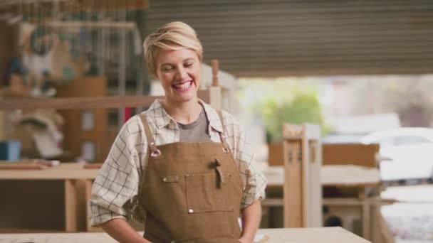 家具工房で働く笑顔の女性見習い大工の肖像画 ゆっくりとした動きで撮影 — ストック動画