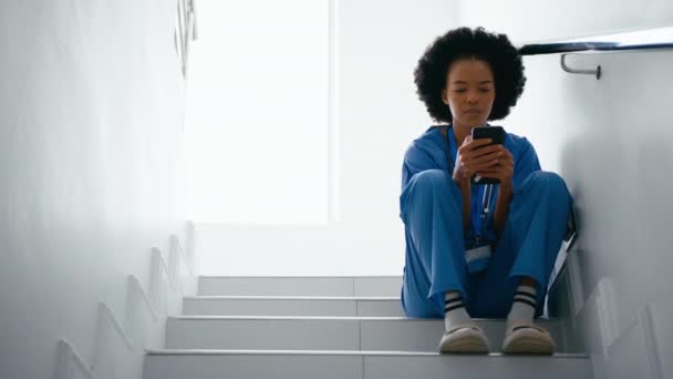 Önlük Giymiş Kadın Hemşire Mesajları Kontrol Ediyor Hastane Merdivenlerinde Kayıyor — Stok video