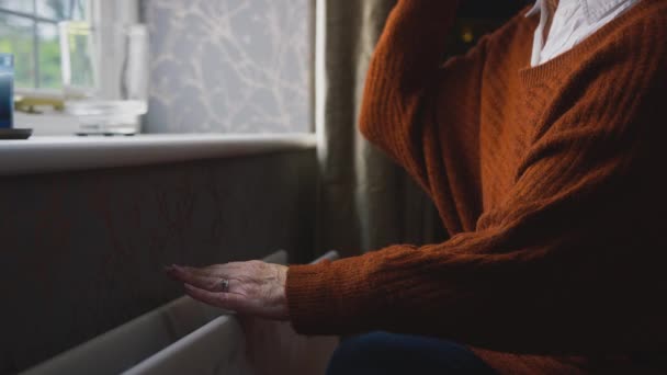 一名老年妇女坐在暖气炉旁 手挽手 试图在能源和生活成本危机中保暖 她喝着热饮 慢动作地打了个寒颤 — 图库视频影像