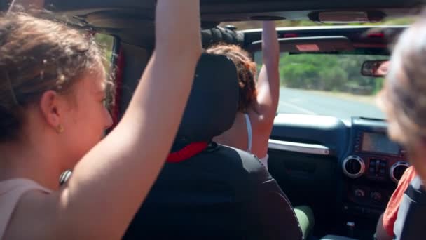 オープントップカーの女性の友人のグループは 田舎を介して道路旅行で笑い お互いに高い5を与えます スローモーションで撮影 — ストック動画