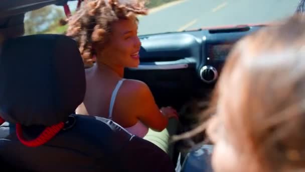 オープントップカーの女性の友人の肖像画 田舎を横断する道路旅行で笑う スローモーションで撮影 — ストック動画