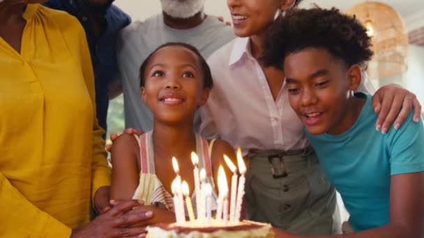 自宅でキッチンに立っている愛する多世代の家族の近くにケーキとろうそくがろうそくを吹き飛ばすように彼女に幸せな誕生日を歌うケーキとキャンドルの誕生日を祝う — ストック動画