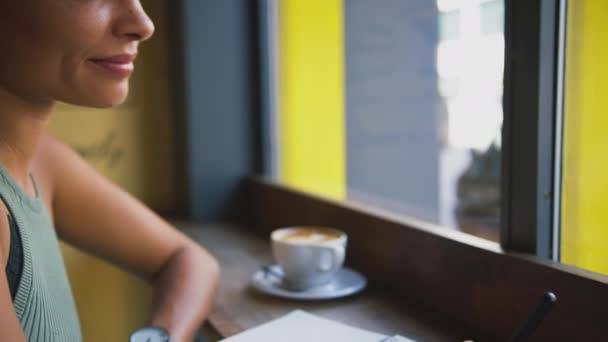 Mujer Sonriente Sentada Ventana Cafetería Escribiendo Cuaderno Filmado Cámara Lenta — Vídeos de Stock