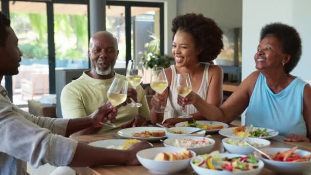 テーブルの周りにシニアの両親と大人の子供を持つ家族は 食事の前にワインで応援しています スローモーションでショット — ストック動画