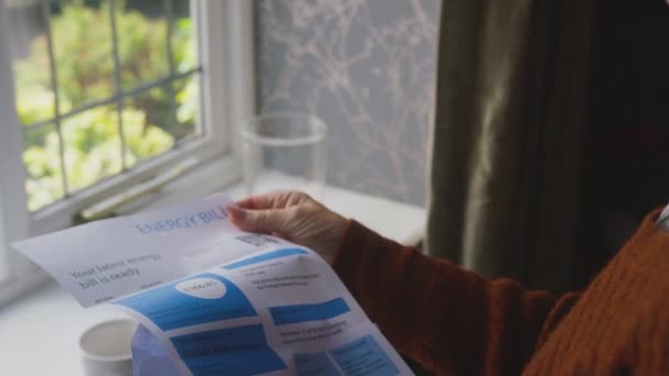 英国のエネルギー法案で自宅の窓に立っているシニア女性は 心配しているように生活危機のコストで スローモーションで撮影 — ストック動画
