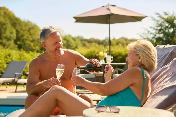 Senior Couple Holiday Swimming Costumes Pouring Champagne Hotel Swimming Pool — Stock Photo, Image