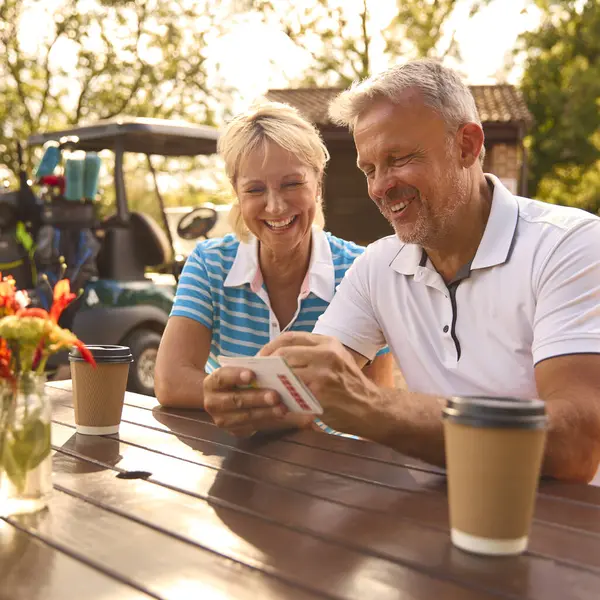 Starsza Para Siedzi Przy Kawie Rundzie Golfa Patrząc Karty Wyników — Zdjęcie stockowe