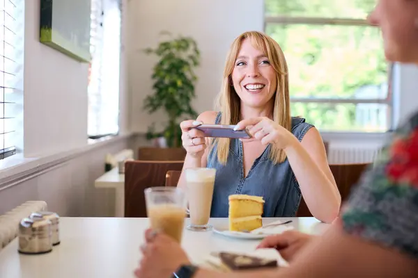Kobieta Kawiarni Przyjacielem Robi Zdjęcie Kawy Ciasta Dla Mediów Społecznościowych Obrazy Stockowe bez tantiem