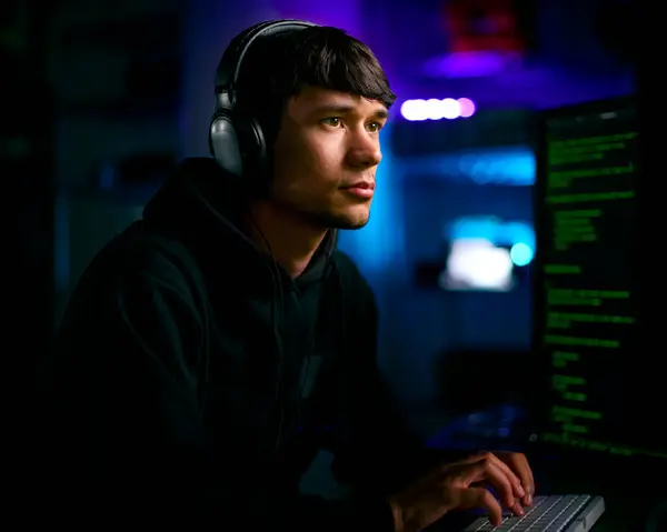 スクリーンの前で座っている男性のコンピュータハッカーの低いキー照明ショットサイバーセキュリティ — ストック写真