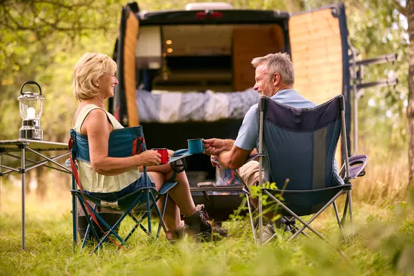 户外篝火边喝咖啡的农村老年夫妇露营背景图 — 图库照片