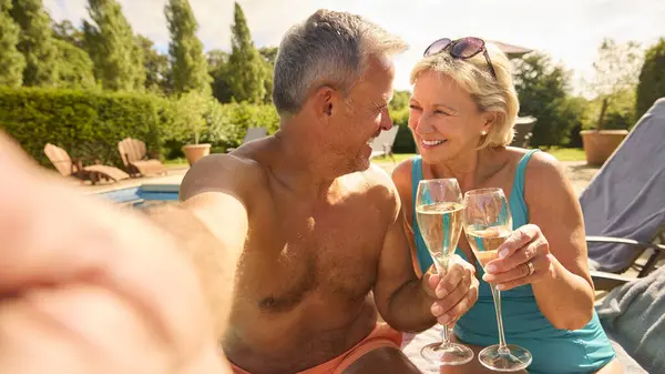 老夫老妻因个人游游泳池喝香槟放松度假的Pov镜头 — 图库照片