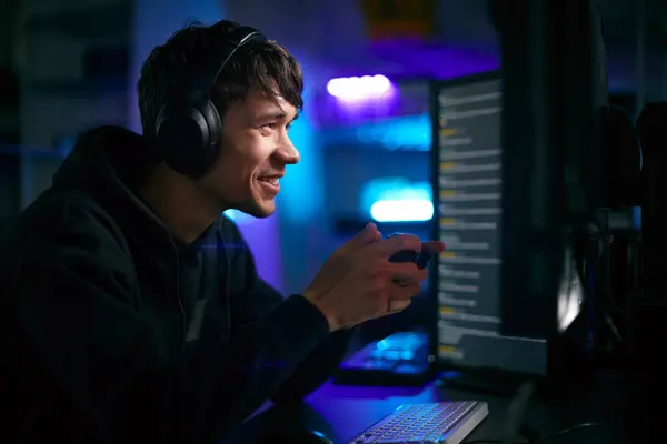 带耳机和控制器的电脑屏幕前男性游戏者的低调照明镜头 — 图库照片
