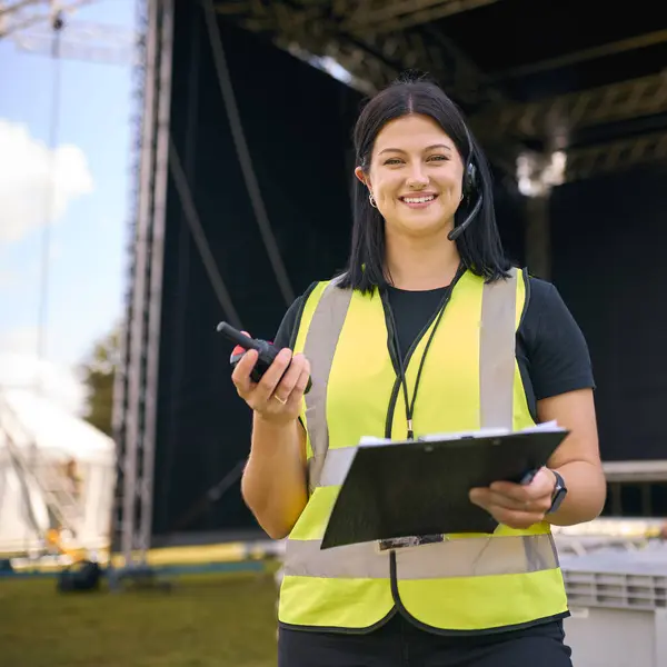 Portrait Of Female Production Worker Setting Up Outdoor Stage For Music Festival Or Concert
