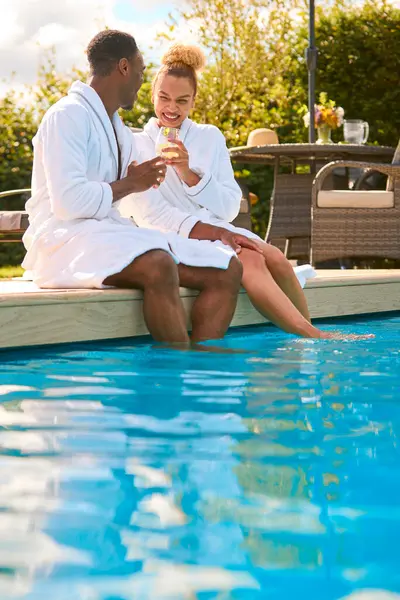 Couple Wearing Robes Outdoors Sitting Drinks Feet Swimming Pool Spa — Stock Photo, Image