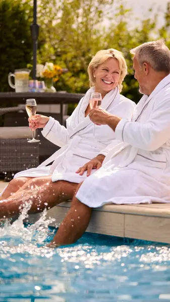 Coppia Senior Accappatoi All Aperto Bere Champagne Piscina Splashing Water — Foto Stock