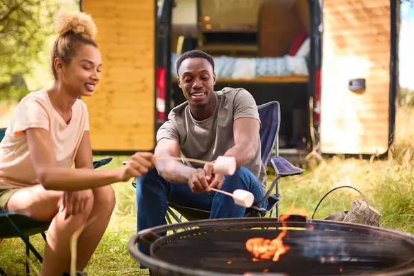 Close Up Of Couple Camping In Countryside With RV Toasting Marshmallows Outdoors On Fire