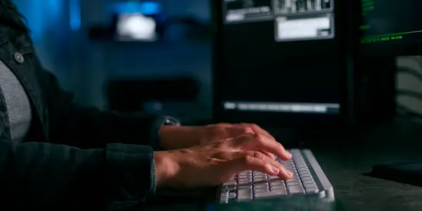 靠近坐在屏幕前破坏网络安全的女性计算机黑客的手 — 图库照片