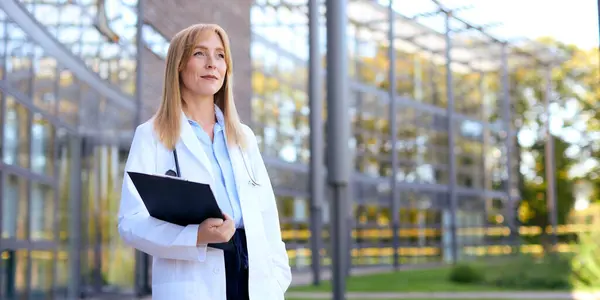 Female Doctor Wearing White Coat Holding Clipboard Standing Modern Hospital — Stock Photo, Image