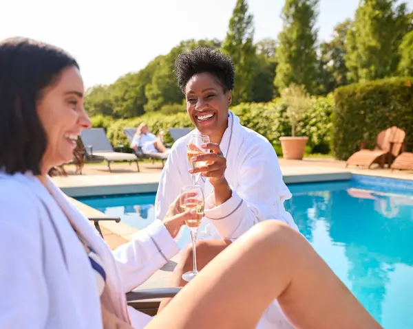 Two Mature Female Friends Wearing Robes Outdoors Loungers Drinking Champagne — Stock Photo, Image