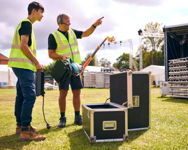 Production Team Unpacking Lights From Flight Case And Setting Up Outdoor Stage For Music Festival