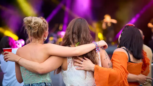 サマーミュージックフェスティバルで踊る3人の女性の友人のリアビュー ストック画像