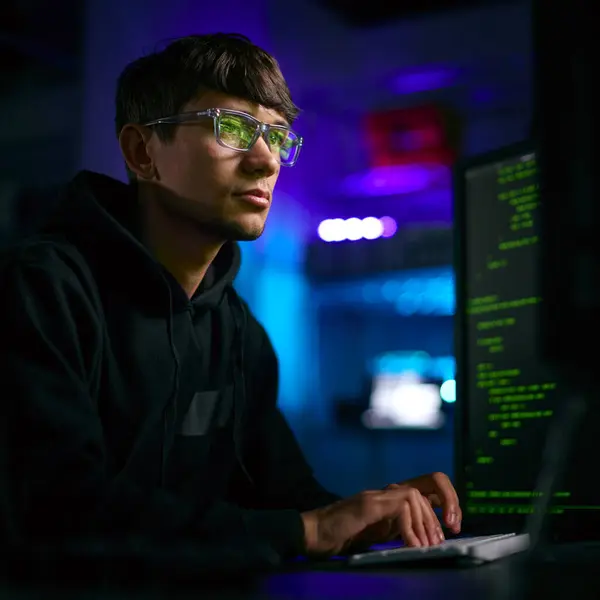 男子计算机黑客坐在屏幕前破坏网络安全的低调照明镜头 免版税图库照片
