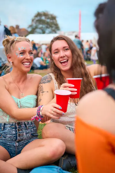 Drei Freundinnen Glitzeranzügen Amüsieren Sich Bei Sommerlichem Musikfestival Mit Getränken lizenzfreie Stockfotos