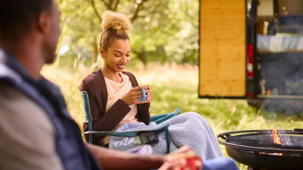 屋外の火によってコーヒーを飲む椅子の座席が付いているカップルのキャンプ — ストック写真