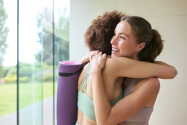 两个女朋友穿着健身服装在健身房或瑜伽工作室见面和拥抱进行锻炼 — 图库照片