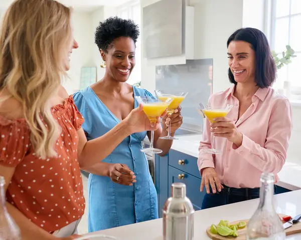 Three Mature Female Friends At Home Celebrating With Cocktails Together
