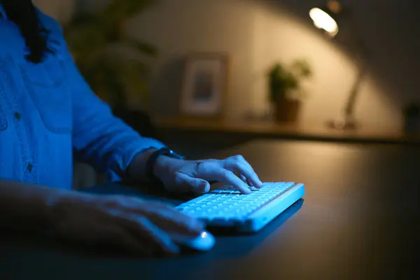 妇女夜间在家用电脑与手指在键盘上打字的近距离接触 免版税图库照片