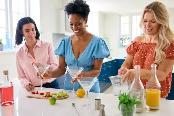 Three Mature Female Friends At Home Having Fun Mixing Cocktails Together