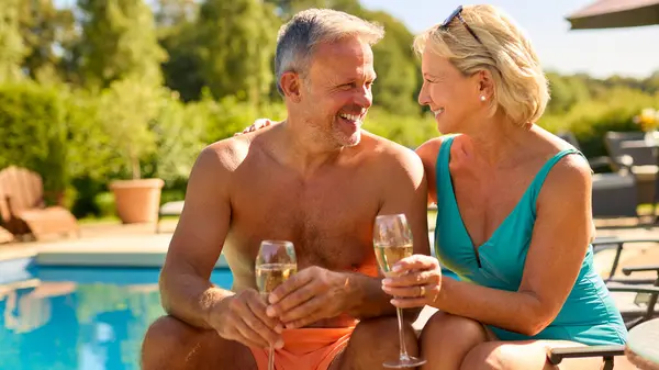 Porträt Eines Senioren Paares Urlaub Badeanzügen Champagner Trinkend Hotelpool lizenzfreie Stockfotos
