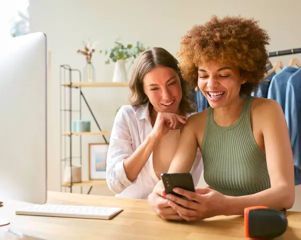 两位女性朋友在家里经营网上时尚生意 在手机上查看社交媒体 — 图库照片