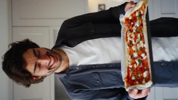 Videoclipul Vertical Tânărului Zâmbitor Bucătărie Acasă Ținând Pizza Proaspătă Pregătită — Videoclip de stoc