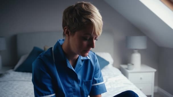 自宅でベッドに座っている涙に近い看護服を着た不幸な女性 ゆっくりとした動きで撮影 — ストック動画