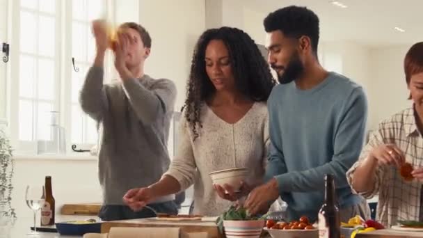 Grupa Przyjaciół Domu Kuchni Rzucanie Kształtowanie Ciasta Dodawanie Polewy Pizzy — Wideo stockowe