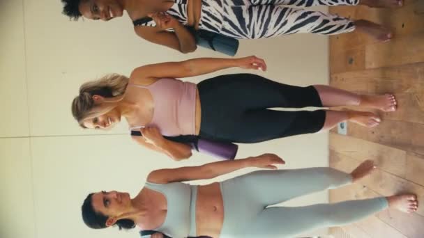 3人の成熟した女性の友人の垂直ビデオ エクササイズマットを運ぶフィットネス服を着て ジムやヨガのクラスでチャット スローモーションで撮影 — ストック動画